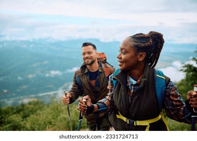 Couple of hikers walking on a hill while using hiking poles. Focus is on African American woman. Copy space. - Powered by Shutterstock