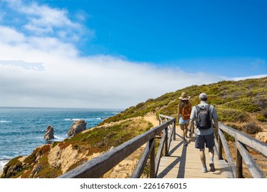 Couple hiking alone on vacation.  Friends walking on wooden pathway by the ocean. Summer mountain coastal landscape.  Garrapata State Park, View from highway 1. Big Sur, California, USA. - Powered by Shutterstock