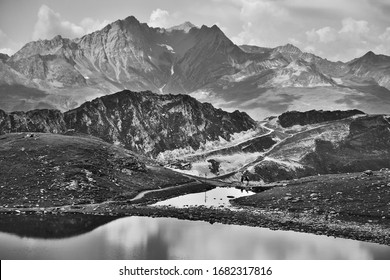 Couple hiking between lakes at French Alps near Arcs 2000 ski station. Summer in Savoie, France. Black white photo.
