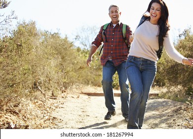 Couple Hiking In Countryside Wearing Backpacks