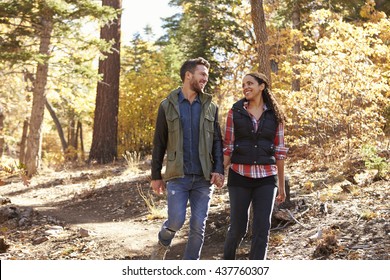 Couple Hiking In A Forest Hold Hands And Look At Each Other