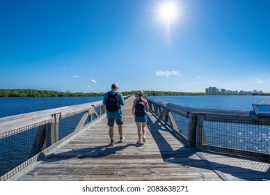 Couple hiking on the pathway over the lake.People walking on the boardwalk leading to Atlantic ocean. MacArthur Beach State Park, North Palm Beach, Florida. USA.