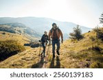 Couple hiking on a scenic mountain trail with backpacks and trekking poles