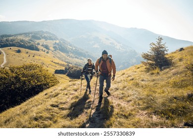 Couple hiking on a scenic mountain trail with backpacks and trekking poles - Powered by Shutterstock