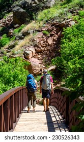 Couple Hiking Over A Bridge In The Colorado Wilderness 