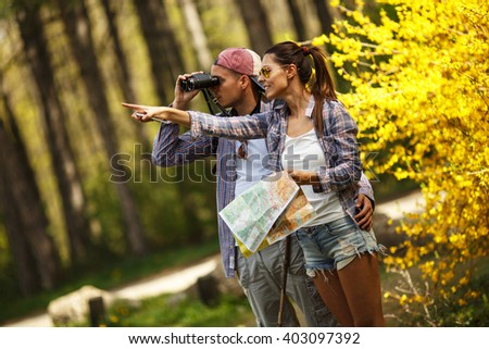 Couple hiking trough forest. Using map to get good direction.