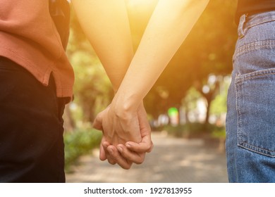 Couple hold hands in the autumn or summer park on sunset. Closeup of loving couple holding hands while walking. Selective focus - Powered by Shutterstock