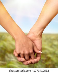 Couple hold hands on green field background