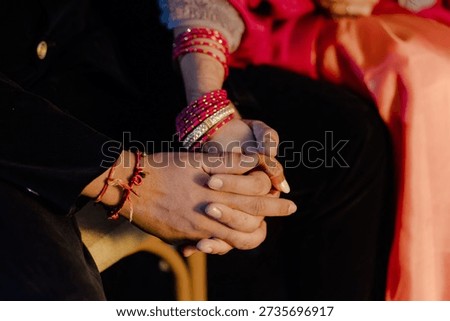 A couple hold hands, symbolizing commitment, love, and togetherness, accentuated by traditional bangles and a promise of a shared future, intimate and heartfelt