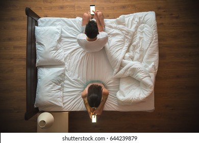 The couple hold a smartphone on the bed. view from above - Shutterstock ID 644239879