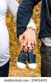 Couple Holding Baby Shoes In Hands