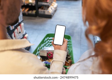 Couple holding cellphone with blank screen at supermarket, mockup for mobile application or website - Powered by Shutterstock