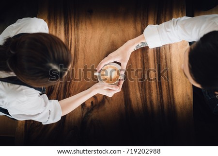 A couple holding coffee on the wooden table