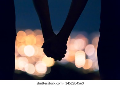 Couple Holding Hands Against City Night Lights. 