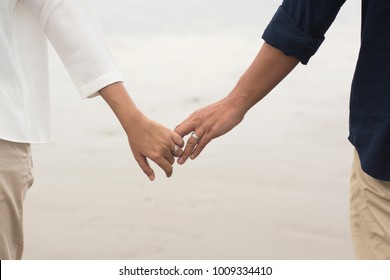 A Couple Holding Hands At Beach.