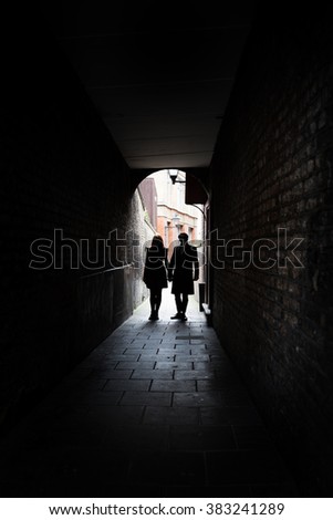 Couple holding hands in dark London alley street grimey