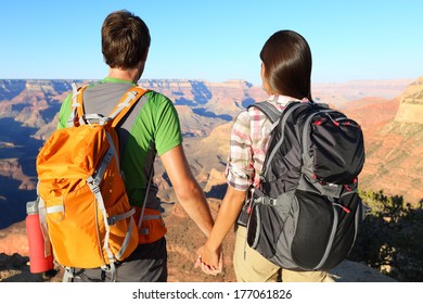 Couple Holding Hands Looking At Grand Canyon. Romantic Hikers Enjoying View And Romance While Hiking Grand Canyon, USA.