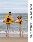 couple holding hands on cold sand coast of the stormy sea