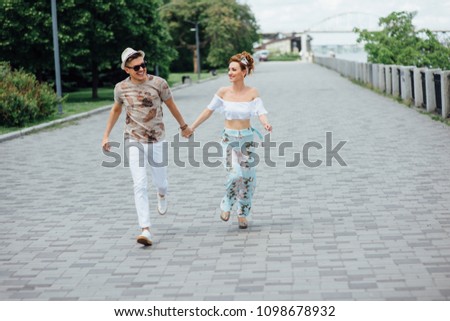 Couple holding hands outdoor. Young couple running