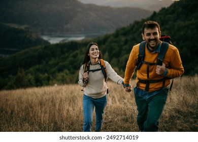 Couple holding hands and trekking together with an amazing view in the background - Powered by Shutterstock