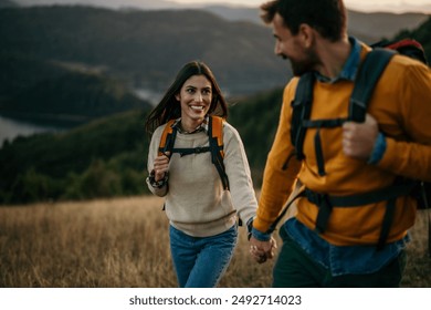 Couple holding hands and trekking together with an amazing view in the background - Powered by Shutterstock