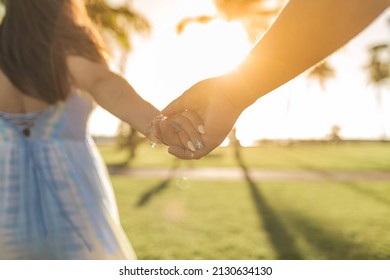 Couple Holding Hands Walking Away Into The Sunset
