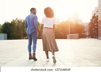 Couple holding hands and walking in the city at sunset