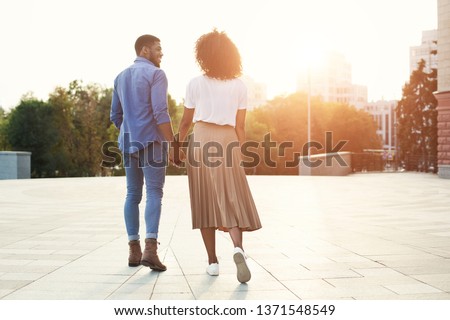 Couple holding hands and walking in the city at sunset