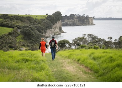 Couple holding hands, walking the Long Bay coastal walk. Auckland.  - Powered by Shutterstock