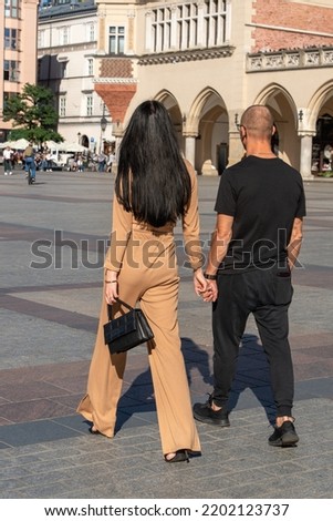 Couple holding hands walking in the old town outdoors on a sunny summer day, man and woman, traditional adult couple, tourists in Krakow, close relationship, love