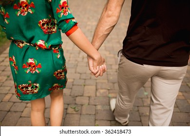 Couple Holding Hands And Walking In A Park