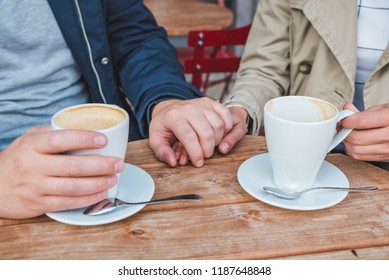 couple holding hands while drinking latte in outdoors cafe. close up - Powered by Shutterstock