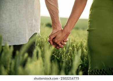 Couple is holding hands while standing on the agricultural field, close up view. - Powered by Shutterstock