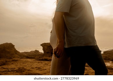 Couple holding hands while standing on rocky shore at sunset near ocean, clouds in sky. couple stands together, holding hands as sun sets behind them. ocean waves crash nearby. moment their connection