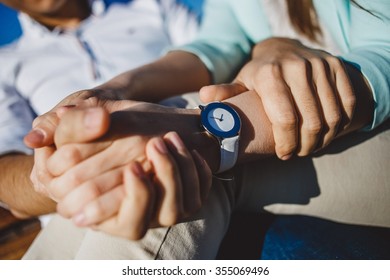 Couple  holding hands with white watches in sunny day.