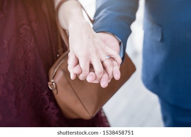 Couple Holding Hands with the Woman Wearing an Engagement Ring