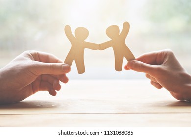 couple holding in hands wooden toy men as symbol of love and friendship