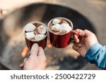 Couple holding hot chocolate outdoors over fire