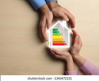 Couple holding house icon with energy efficiency rating at table, top view with space for text - Powered by Shutterstock