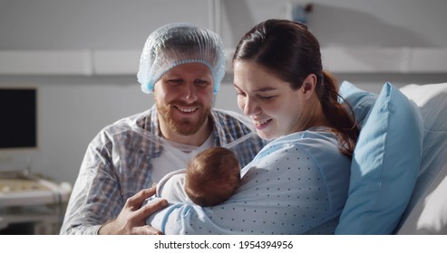 Couple Holding Newborn Baby In Maternity Hospital After Childbirth. Cropped Shot Of Happy Young Parents Holding Infant Baby In Hospital Ward