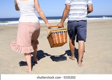 Couple Holding Picnic Basket At Beach