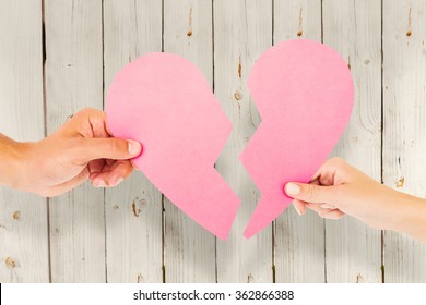 Couple holding two halves of broken heart against wooden background