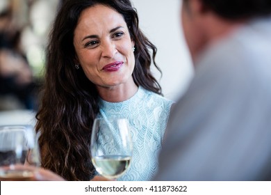 Couple Holding Wine Glass And Interacting At Dining Table In The Restaurant