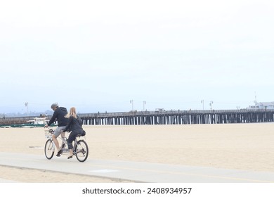 Couple in holidays cycling going on a bike ride on the beach.
 - Powered by Shutterstock