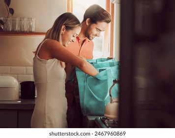 Couple home after grocery shopping at supermarket store. Retail consumer, sustainable shopper and young people unpacking and checking food products, goods and groceries from reusable bag in a kitchen - Powered by Shutterstock