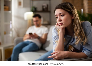 Couple at home after having a fight. Sad depressed woman sitting on sofa