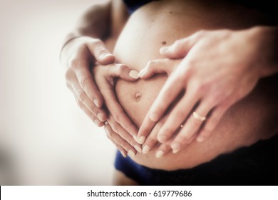Couple at home holding a pregnant woman's belly