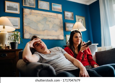 Couple At Home Watching TV.Remote Control Fight Won By Girlfriend.Boyfriend Bored By TV Program.Watching Her Favorite Show/film.Chick Flick Movie.Binge Watching Television.Relationship Home Problems.