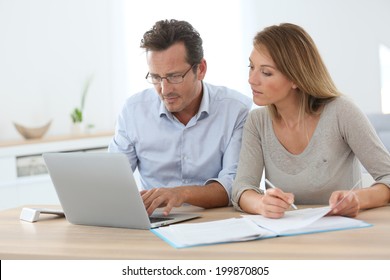 Couple At Home Working On Laptop Computer