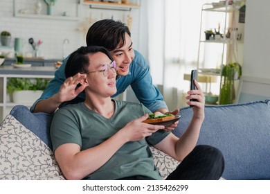 Couple Homosexual Making A Video Call Or Facetime With Smartphone Showing Healthy Food They Make Yourself. Asian Gay Couple Happy And Having Romantic Moment Together At Home. Lifestyle Concept